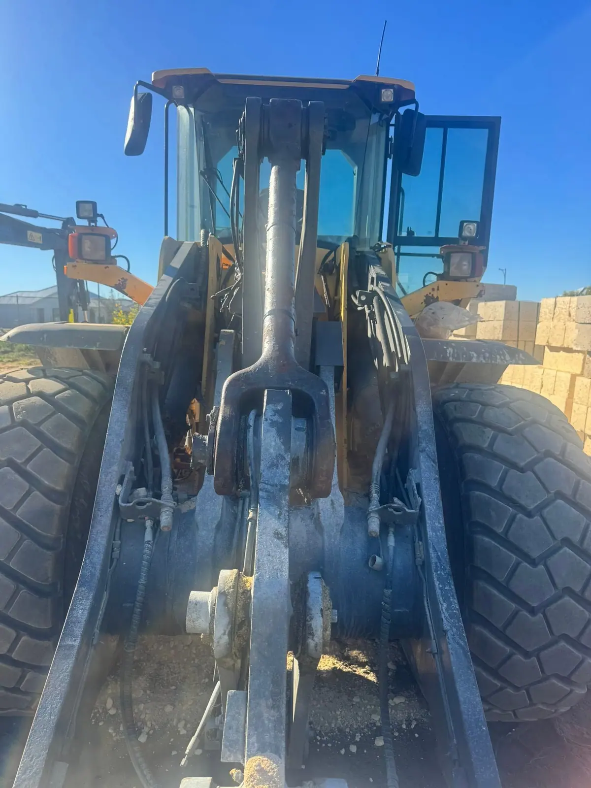 Wheel loader lift arm and pivots under a clear blue sky after the work.