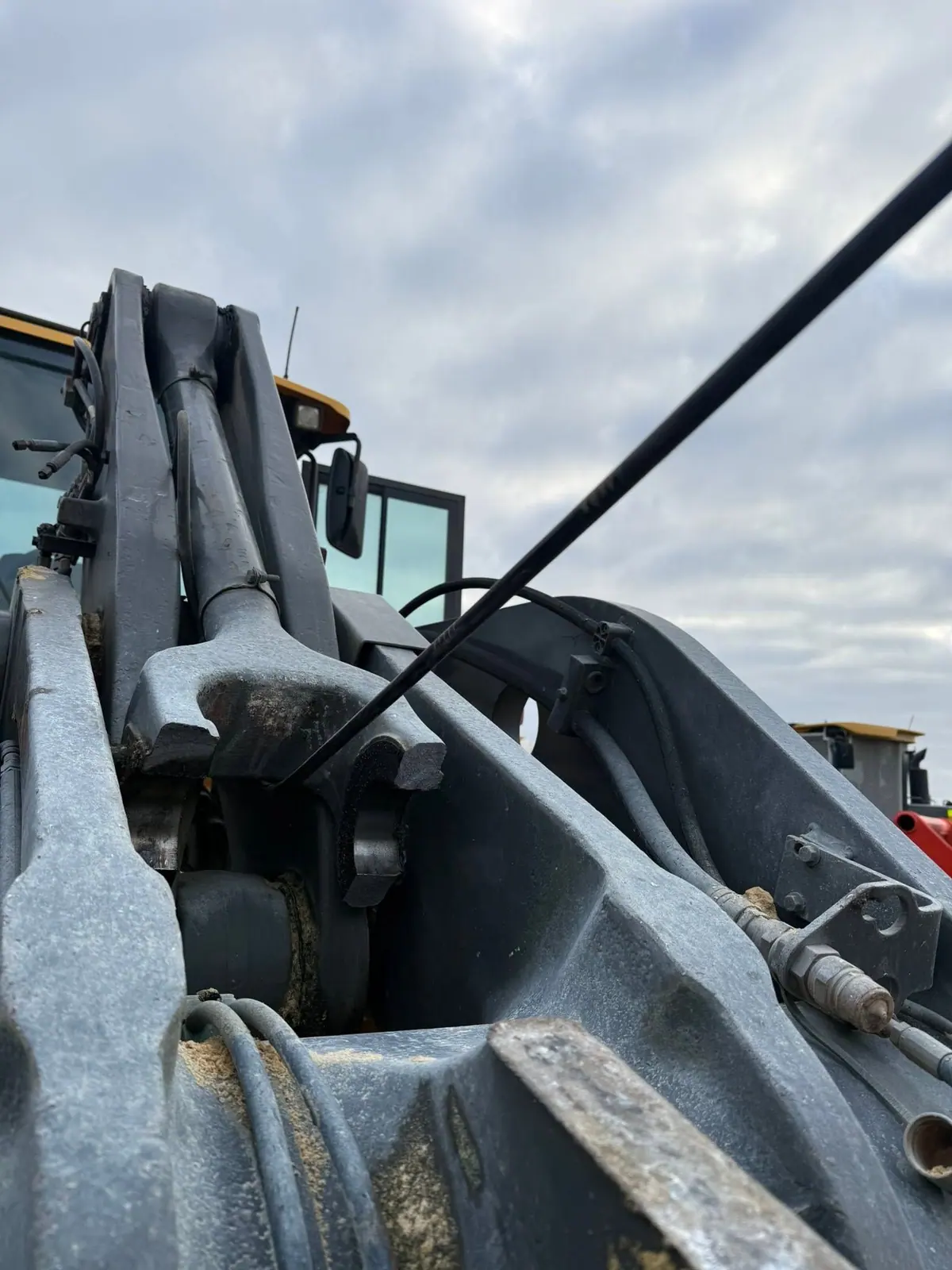 Wheel loader lift arm pivots under a cloudy sky before the work.