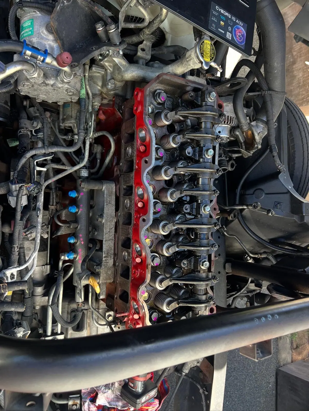 The refitted valve train and rocker assembly on a red Hino engine with the cover off.